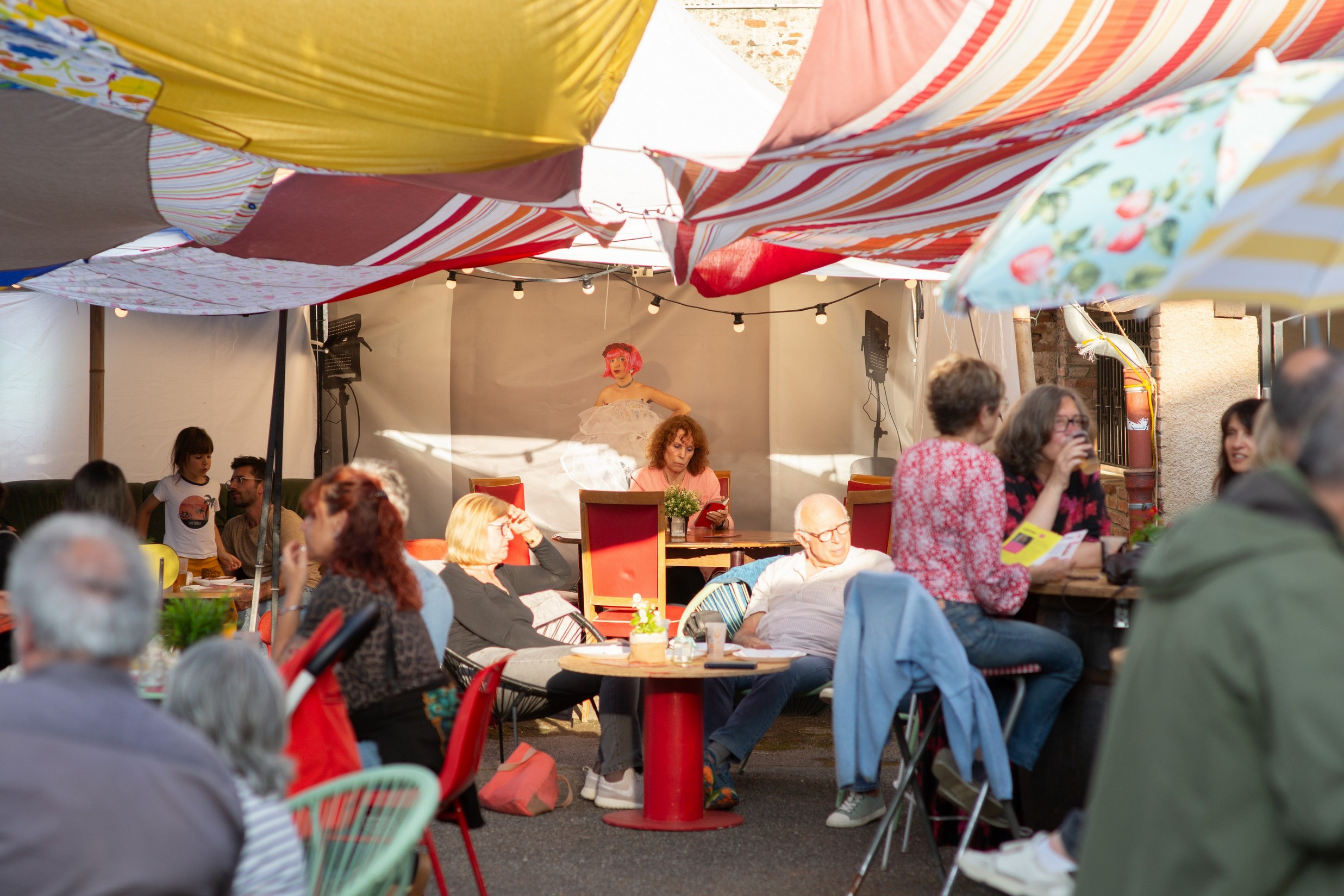 PERSONNES ASSISES AU MILIEU DU FESTIVAL AVEC UN RAYON DE SOLEIL QUI VIENT BAIGNER LA PHOTO